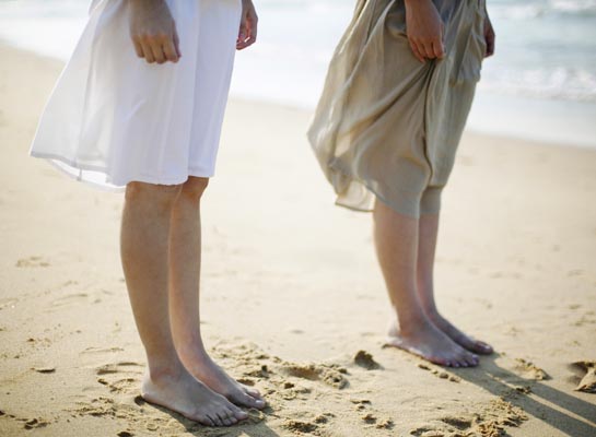 Two Women Standing Side by Side on Sandy Beach